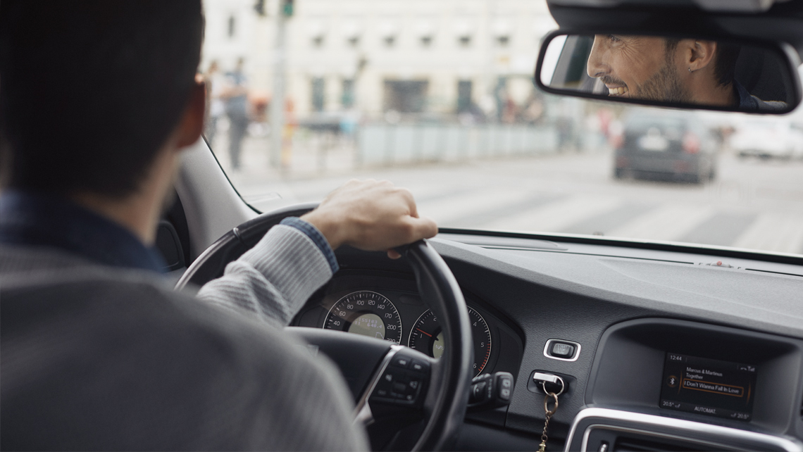 A person driving a car and smiling.