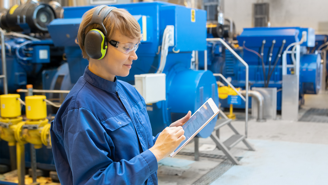 A factory worker looking at a tablet dashboard.