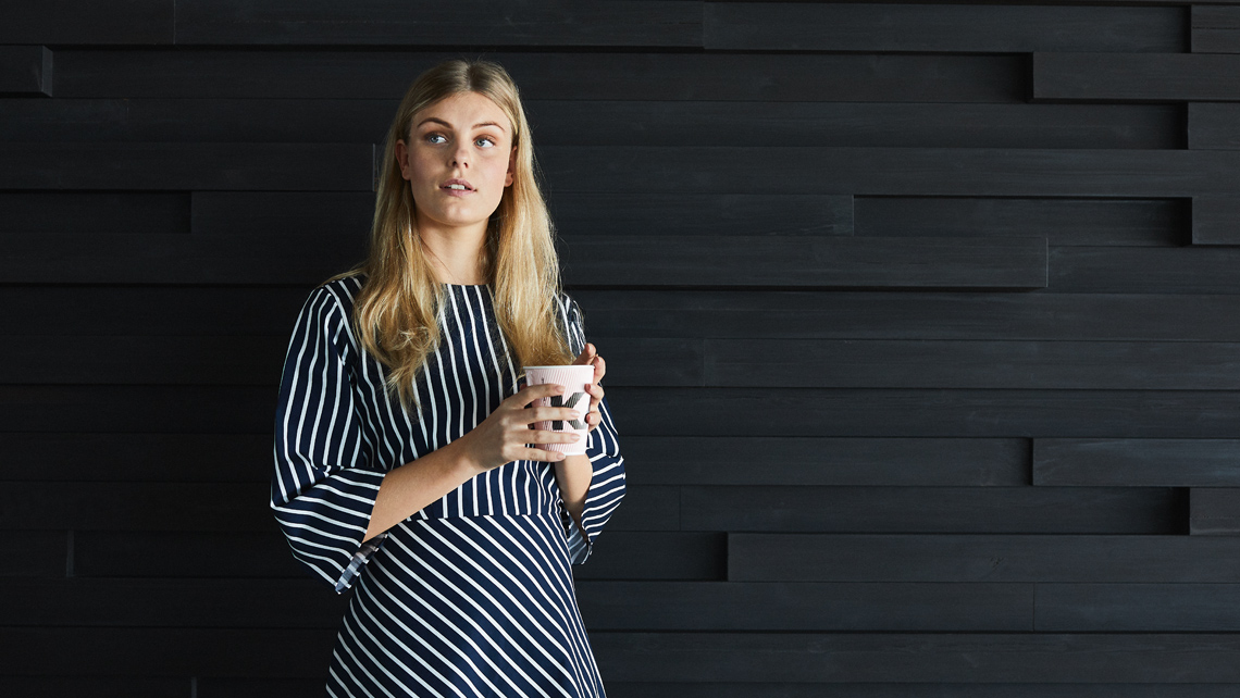 A person holding a coffee cup standing.