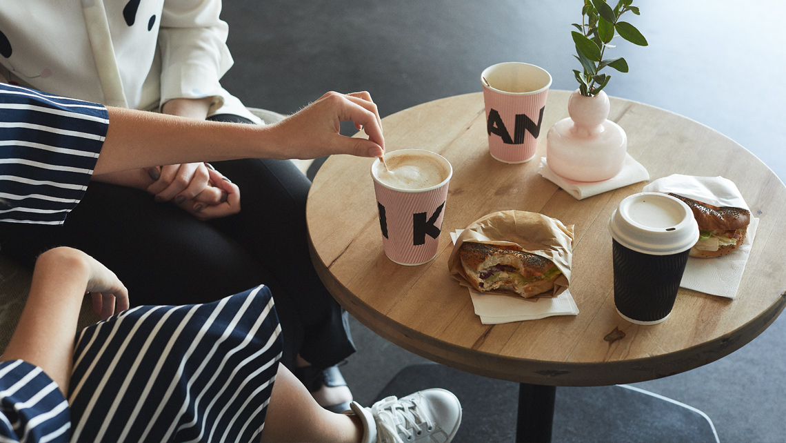 Two persons by the small coffee table with papercups.