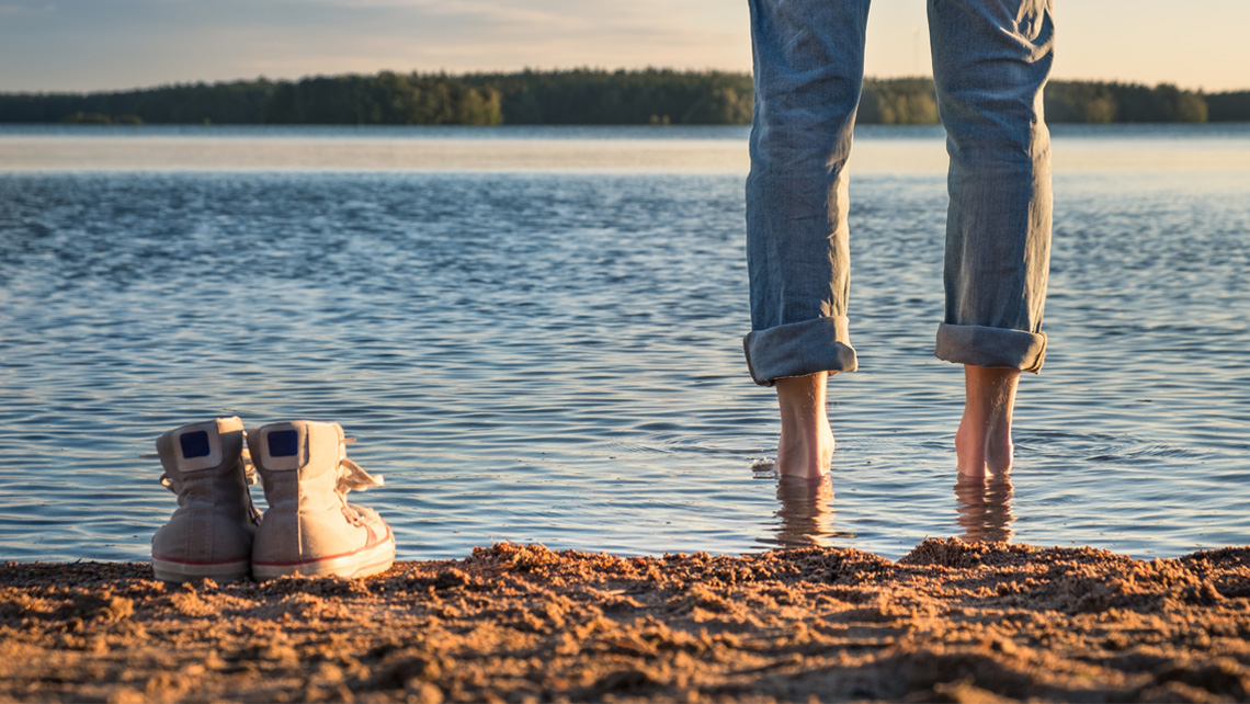 Wading in a water with jeans sleeves rolled up.