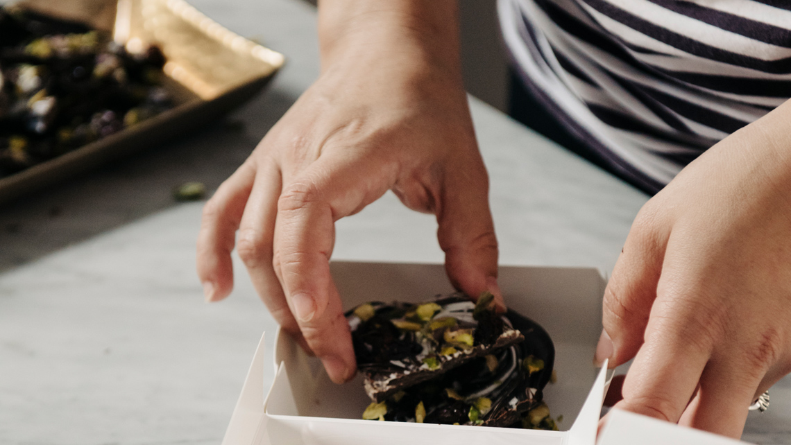 A close up of a person packing pastry to a carboard box.