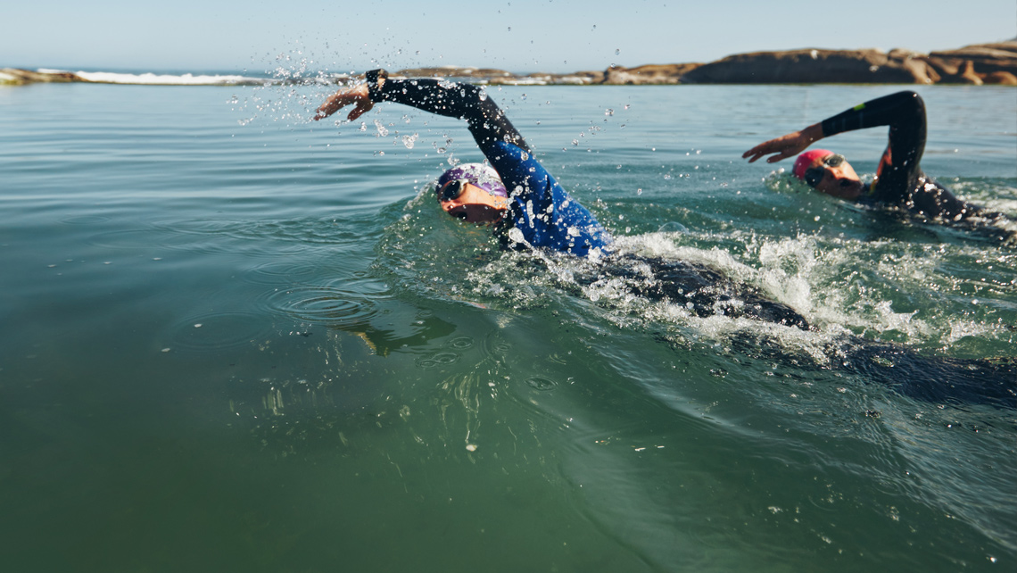 Athletes practicing swimming for triathlon in a sea.