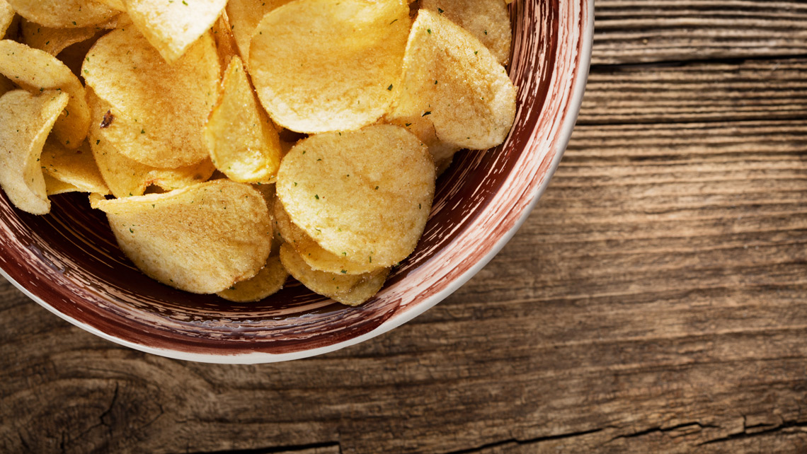 Chips on the plate on a wooden table.