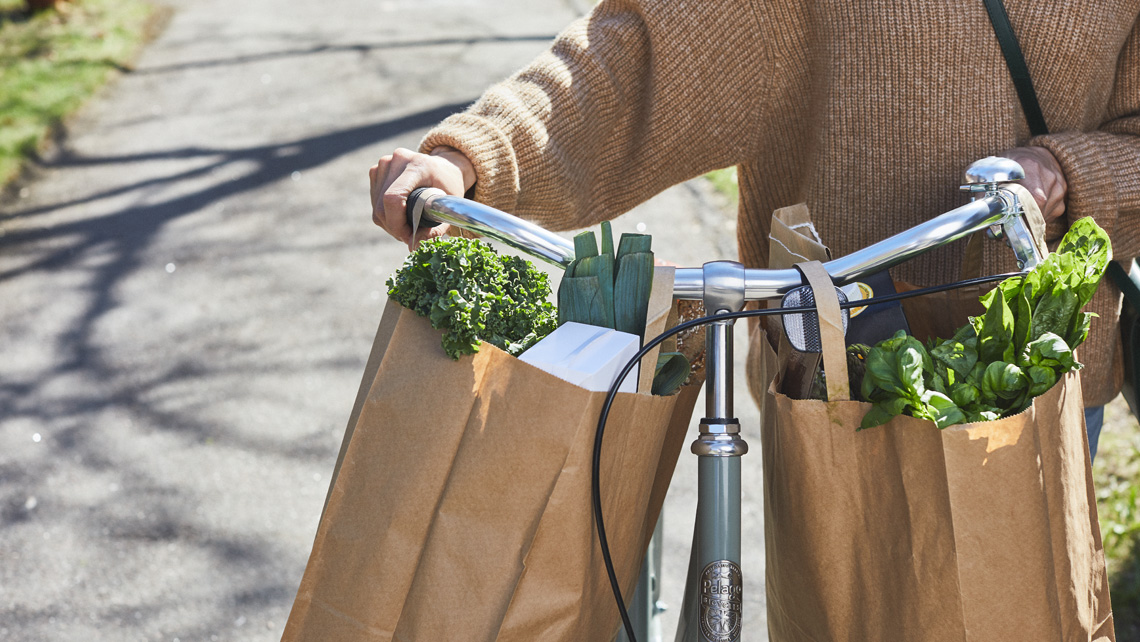 Paper shopping bags hanging on a bicycle rail.