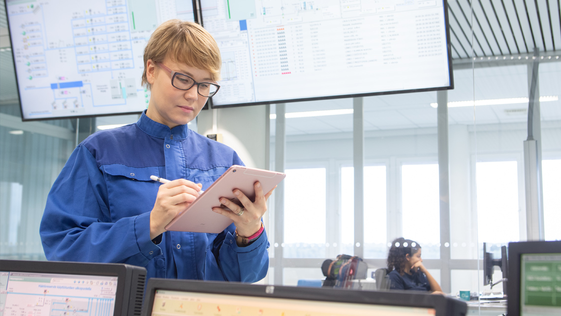 Two workers in a factory monitor room.