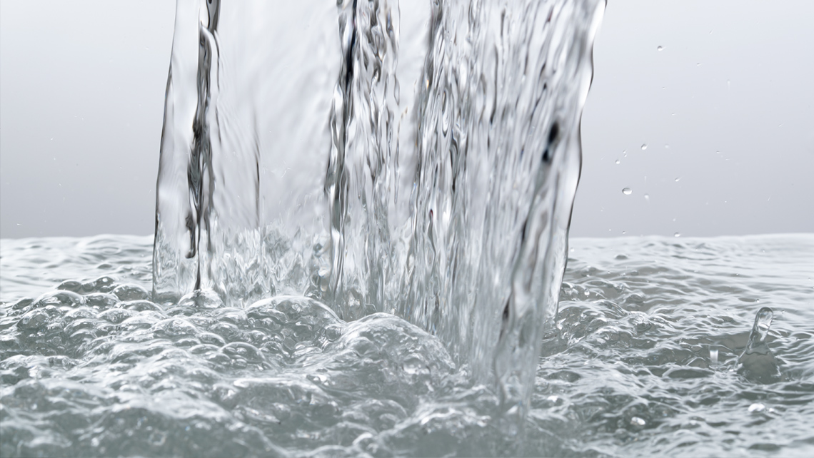 Close up of water pouring down in neutral grey background.