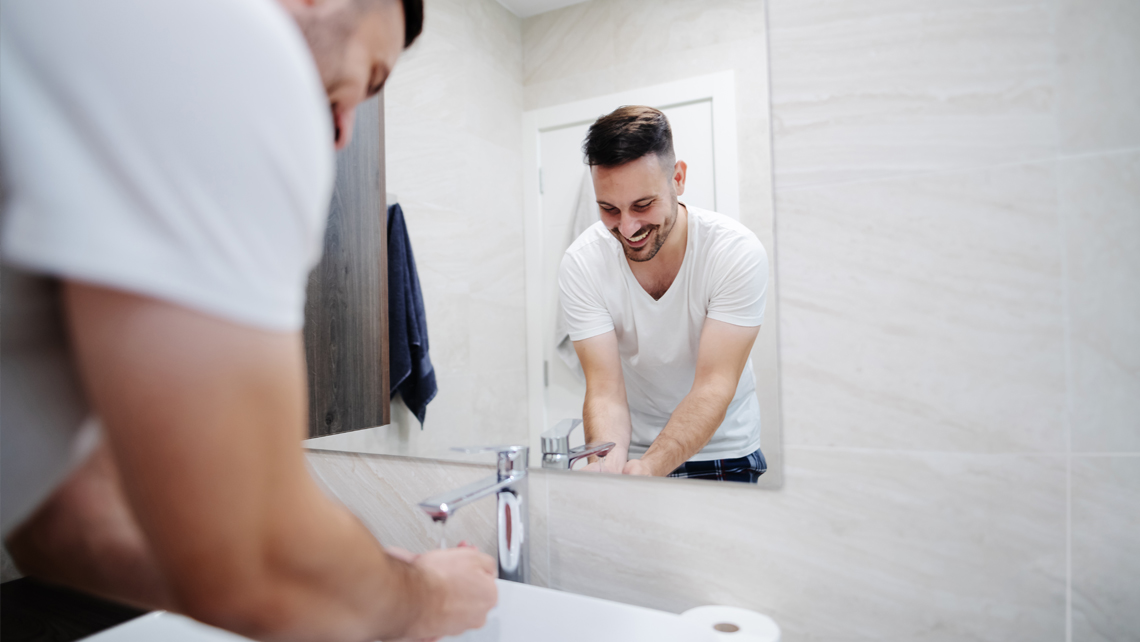 A person washing hands in a bathroom.