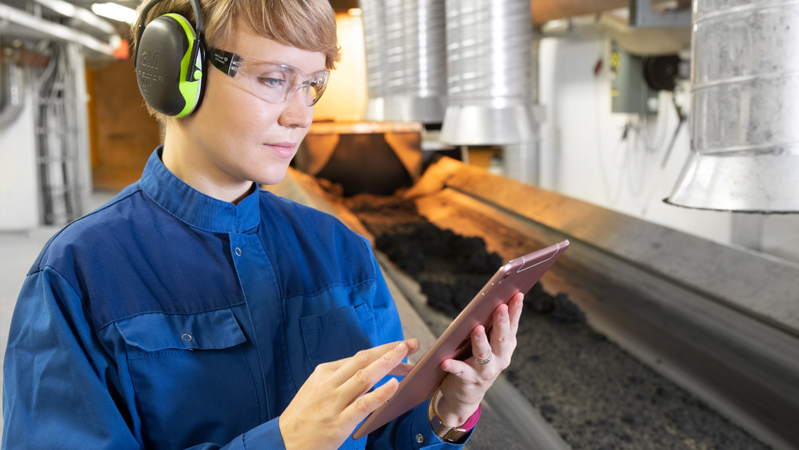 A person holding a tablet in a factory.