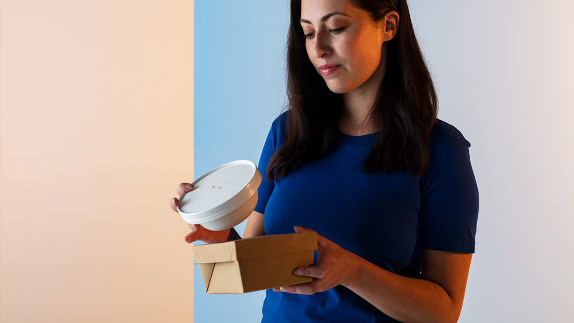 A person holding two food packages.