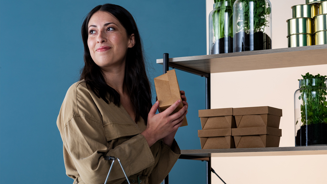 A person smiling and holding a brown food package.