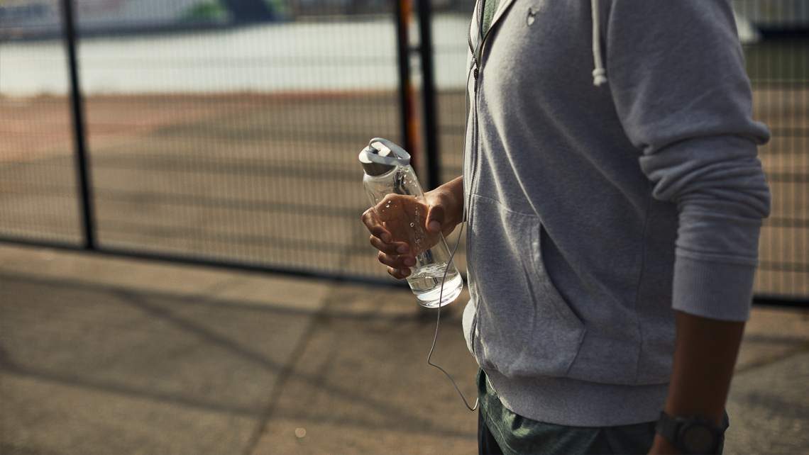 A close up of a jogger holding a transparent water bottle.
