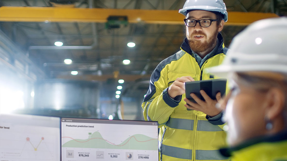 Two factory workers focusing on Predictive Wet End dashboard.