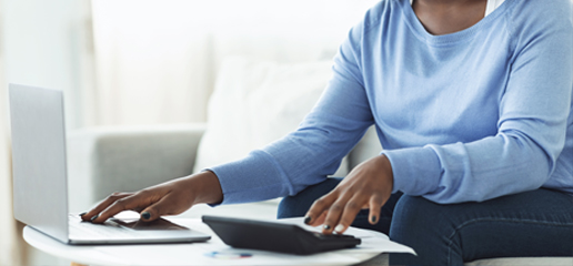 A person using a calculator and a laptop.