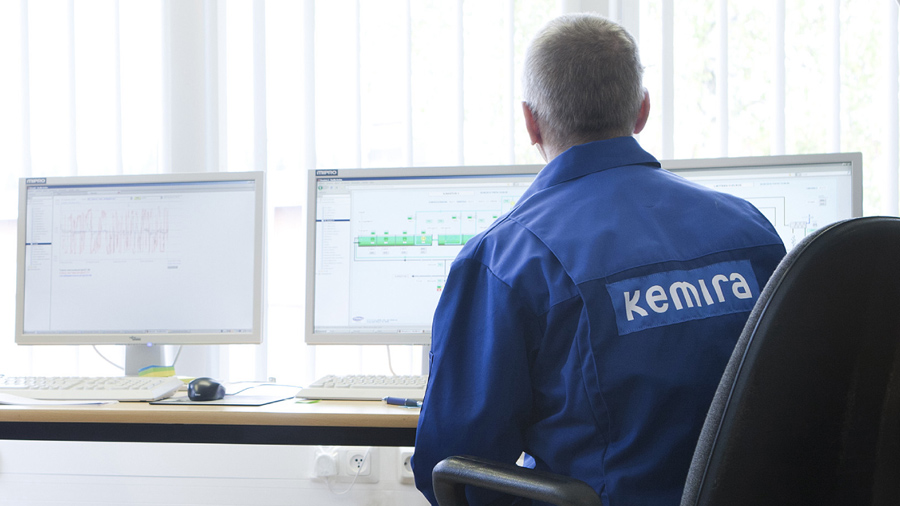 A worker looking at three monitors.