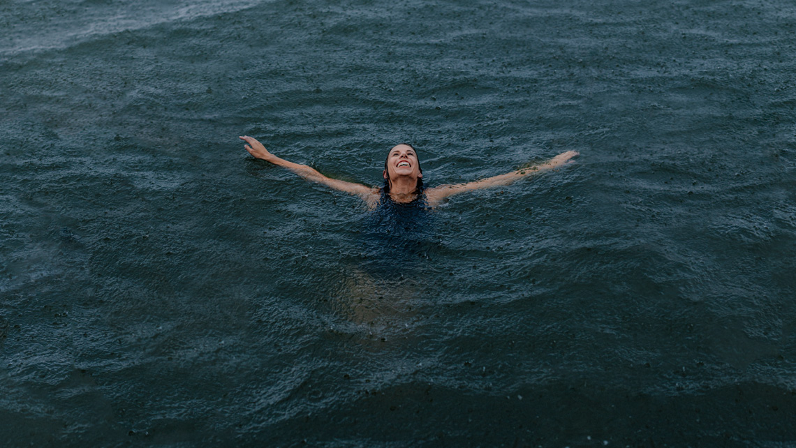 A person swimming in the sea and smiling.