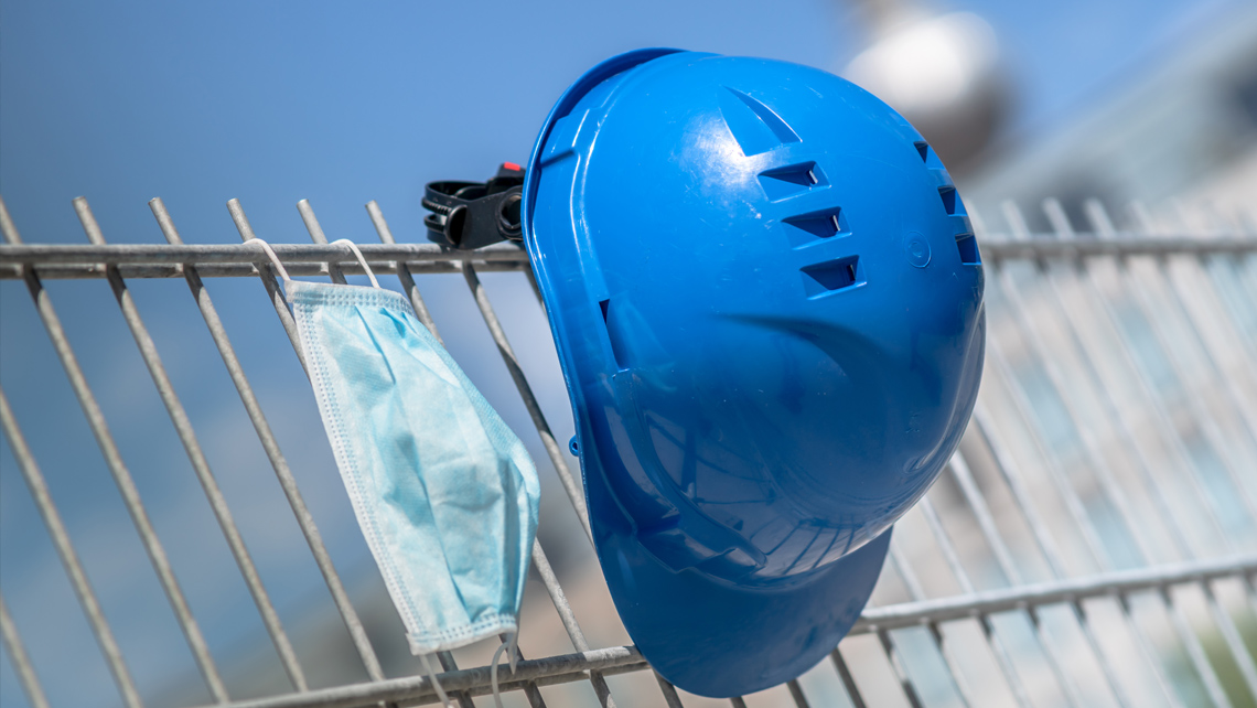 A blue helmet and a mask hanging on a fence.