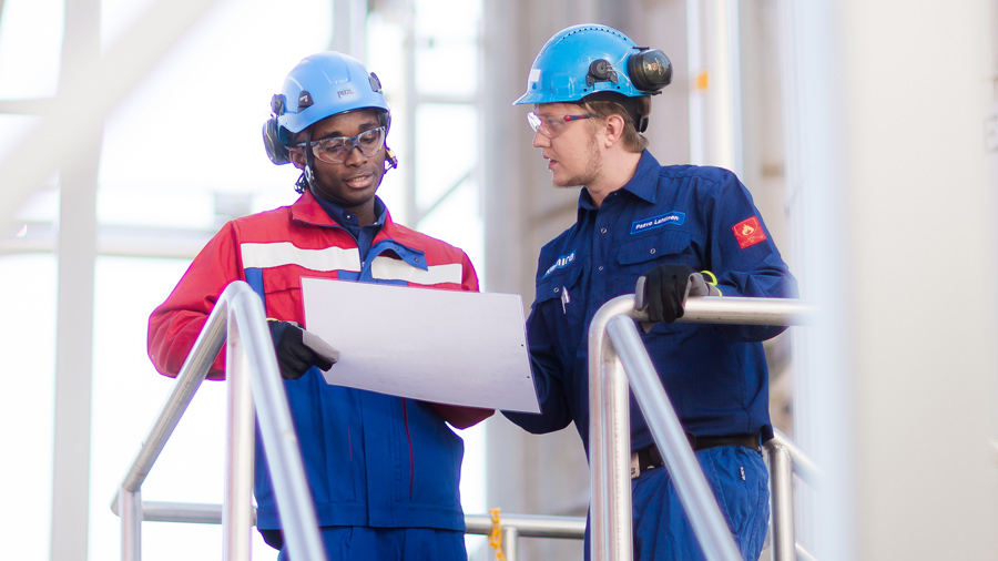 Two factory workers looking at the paper.