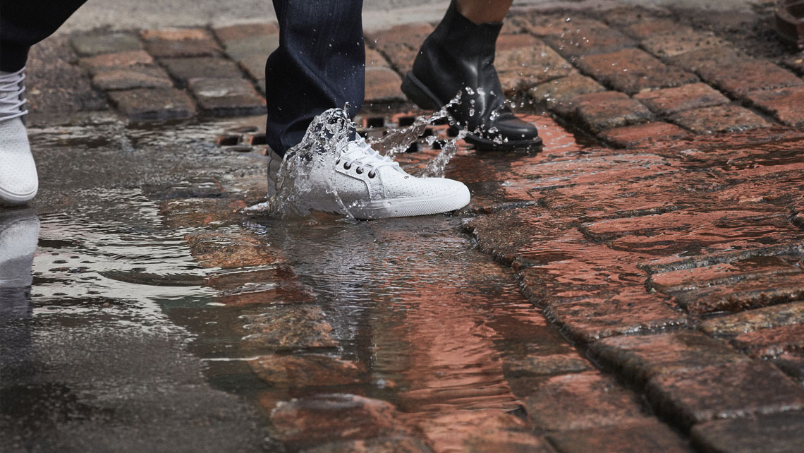 Feet walking through puddle water splashes.