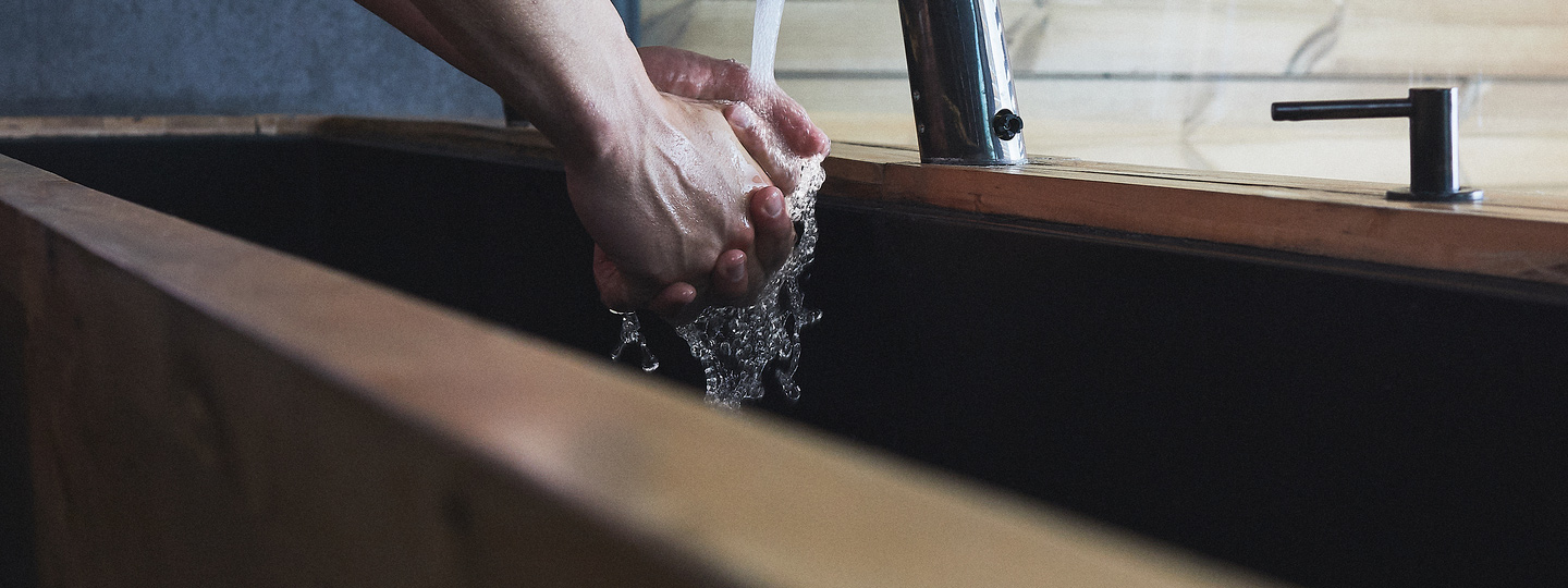 A person washing hands in a bathroom sink.