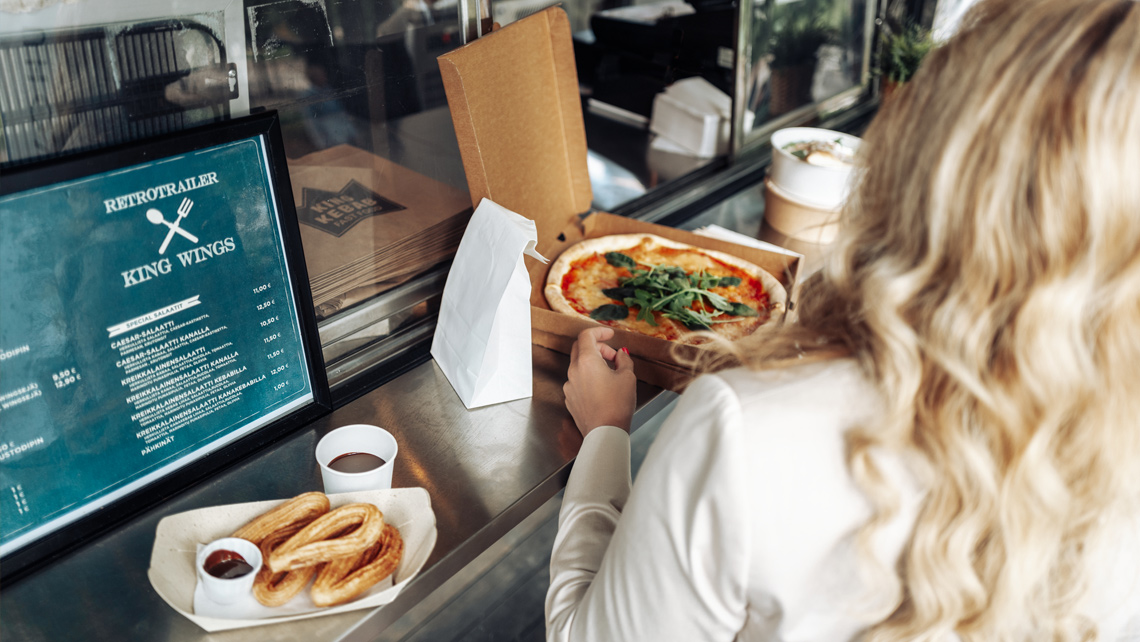 Open pizza box and other takeaway food in brown cardboard packages.