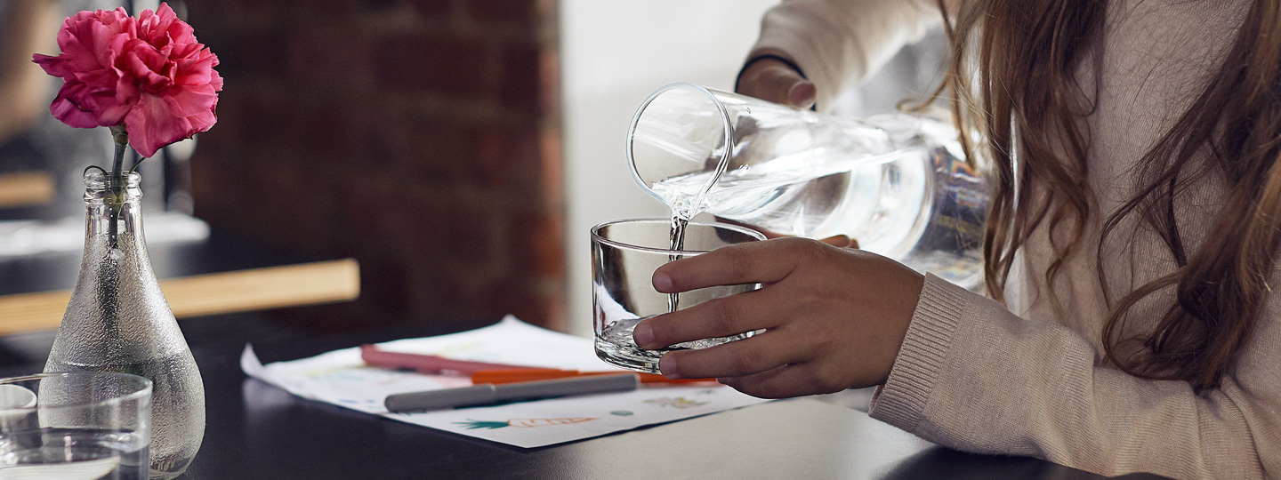 A person pouring water to a glass.