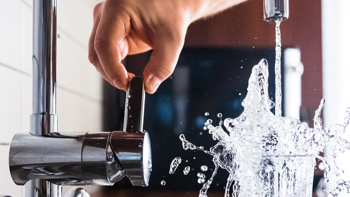 A person pouring water from a tap.