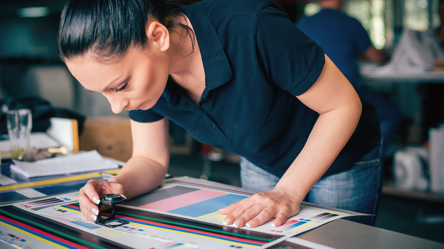 A person reviewing print quality with a loop.