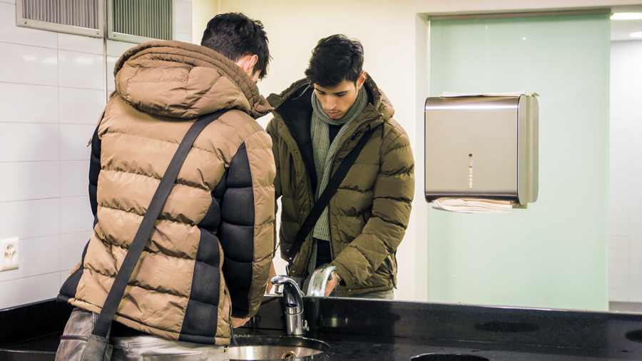 A person washing hands in a restroom.