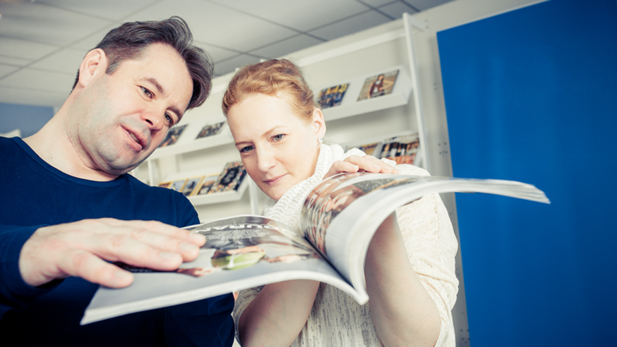 Two persons checking magazine print and paper quality.