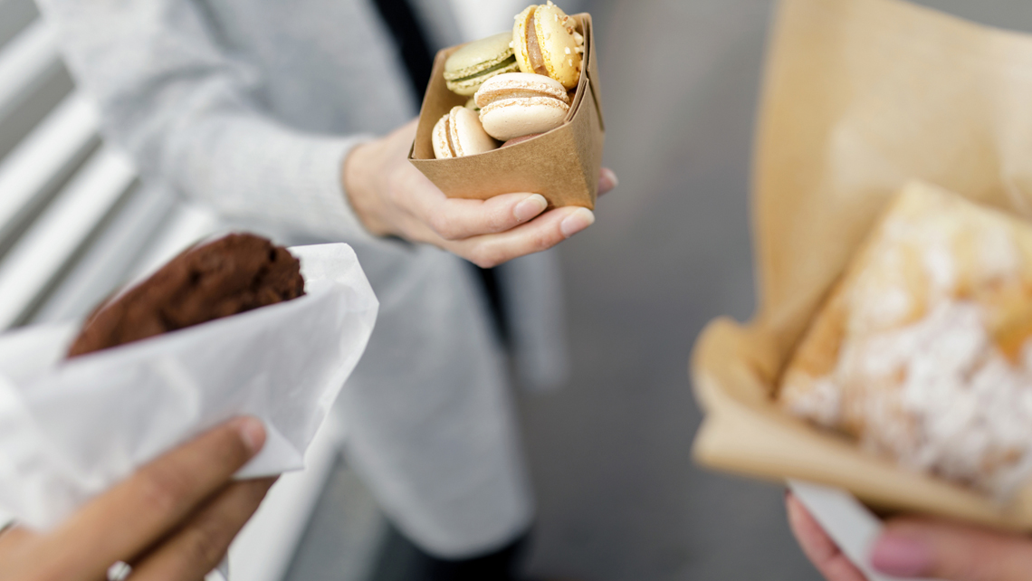 Persons holding pastries in paper and board packages, featuring Kemira's barrier chemistry.