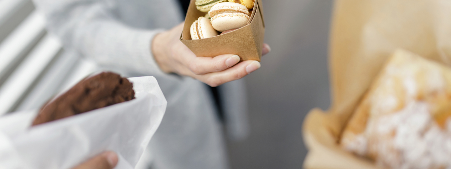 Three persons holding sweets in paper.