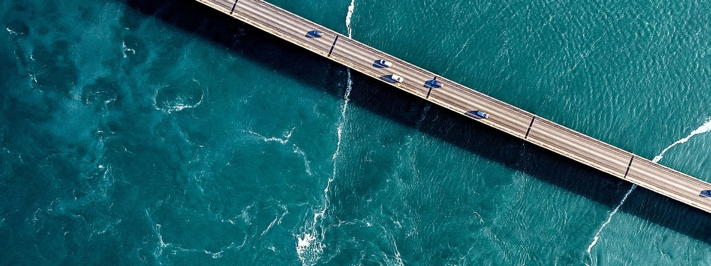 Cars on a bridge middle of water.