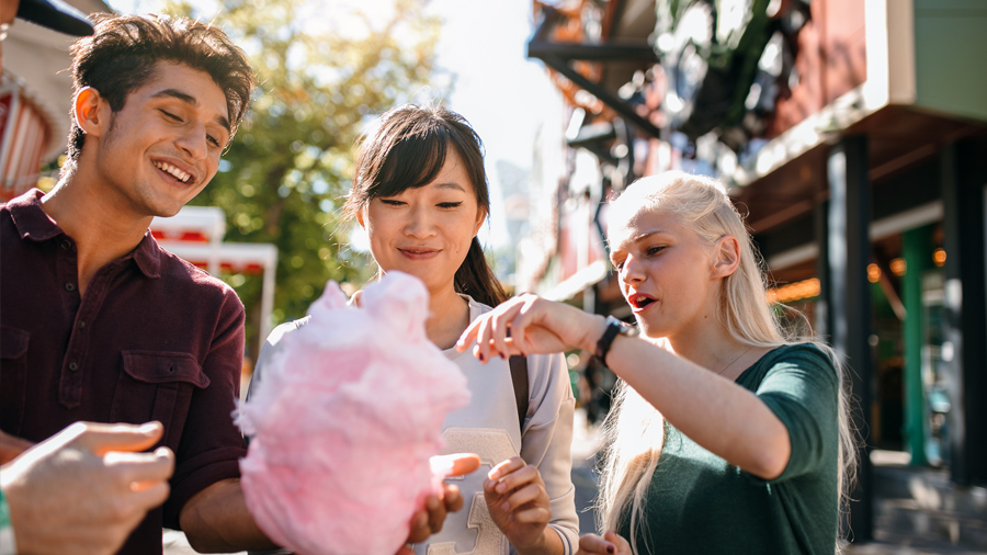 Three persons eating from a pink cotton candy.