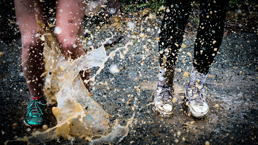 Children jumping on a water puddle.