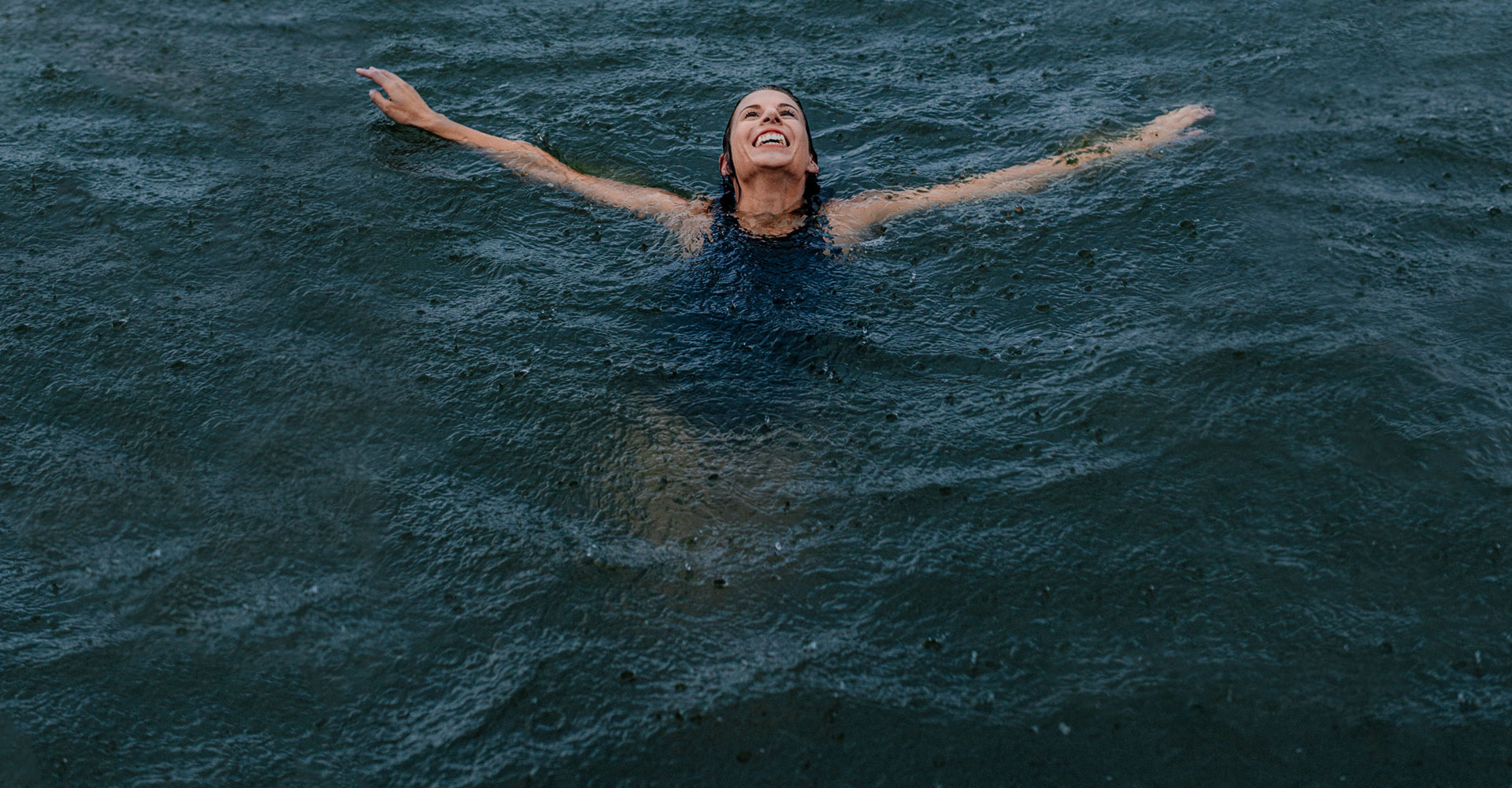 A person smiling and swimming in water.