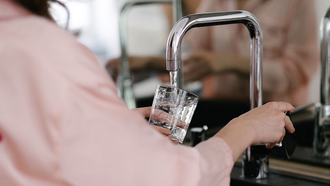 Person pouring tab water into glass.