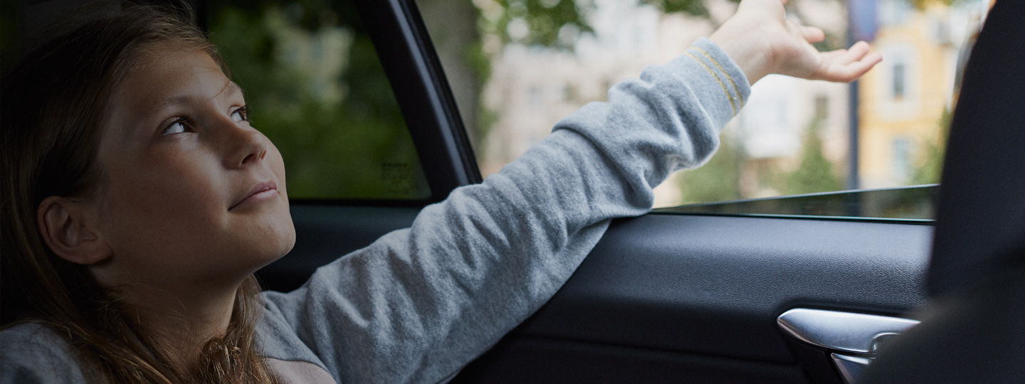 A child sitting in the car hand outside the window.