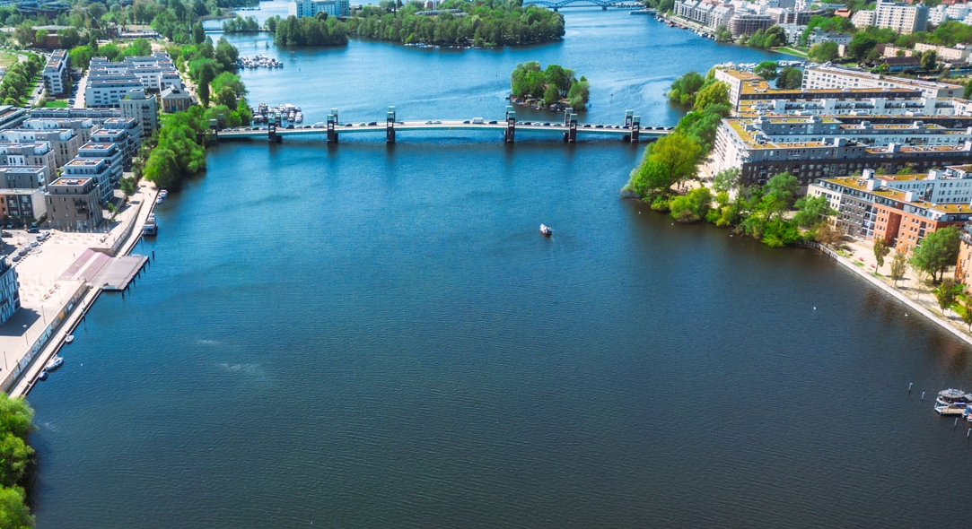 Aerial view of broad canal in city center with bridges and parks.