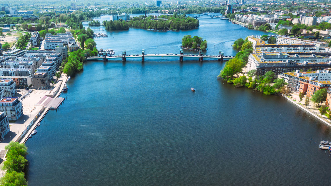 Aerial view of broad canal in city center with bridges and parks.