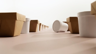 Disposable paper and plastic food containers arranged in rows on a pink surface.