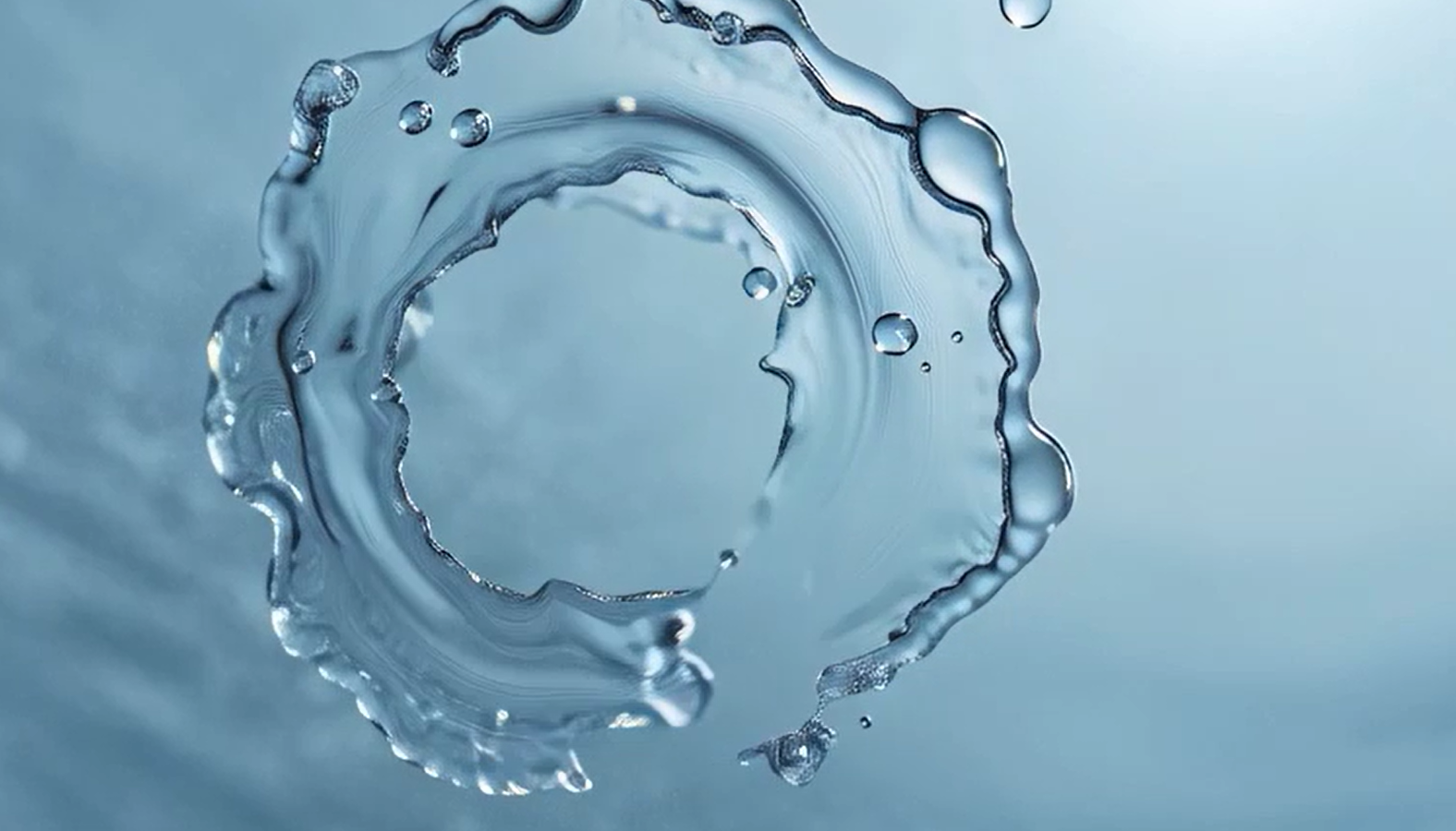 Close-up of a circular water splash forming a ripple ring on a light blue background, symbolizing clean water and sustainable innovation by Kemira.